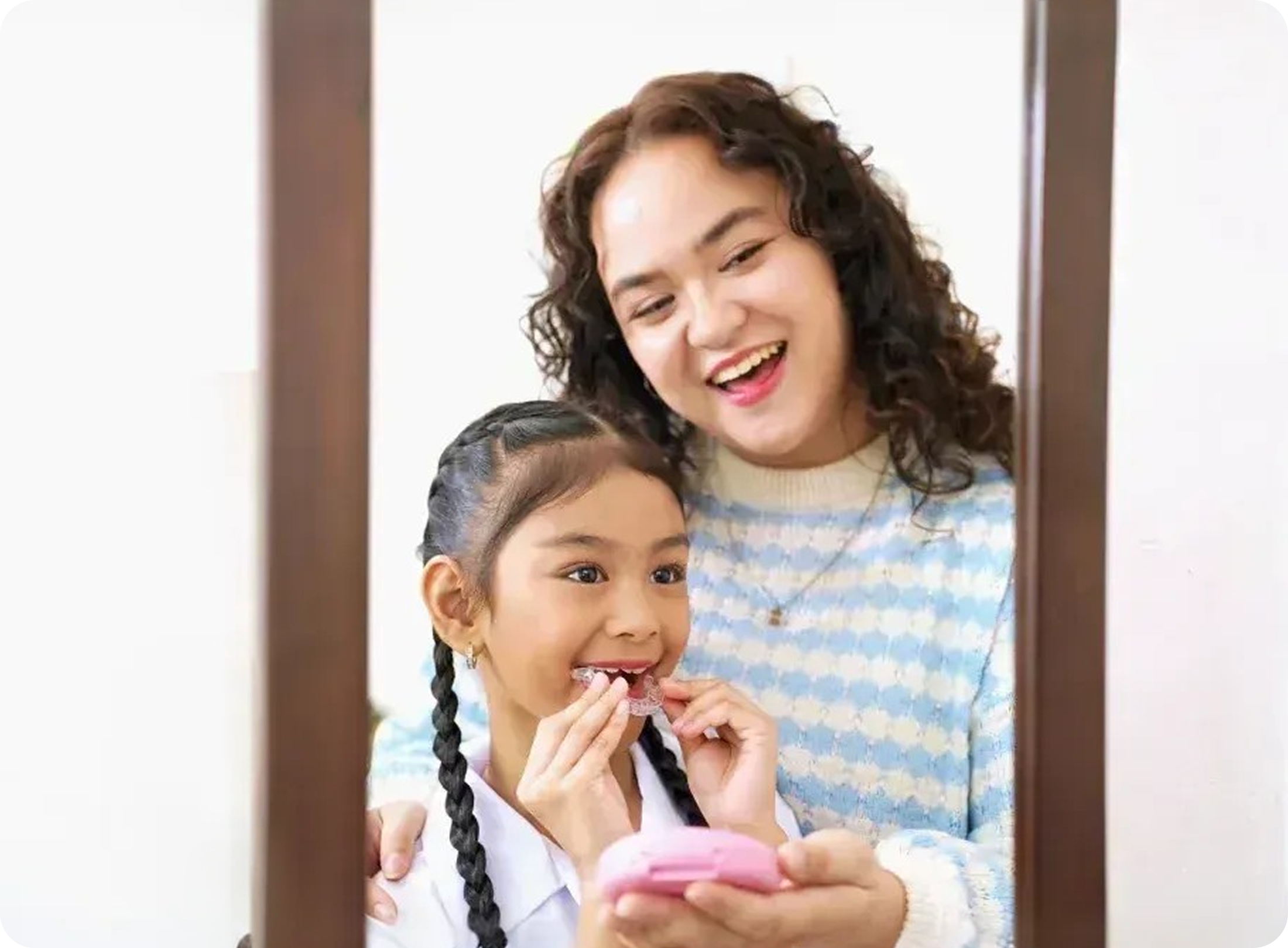 Child holding clear aligners for kids with parent support